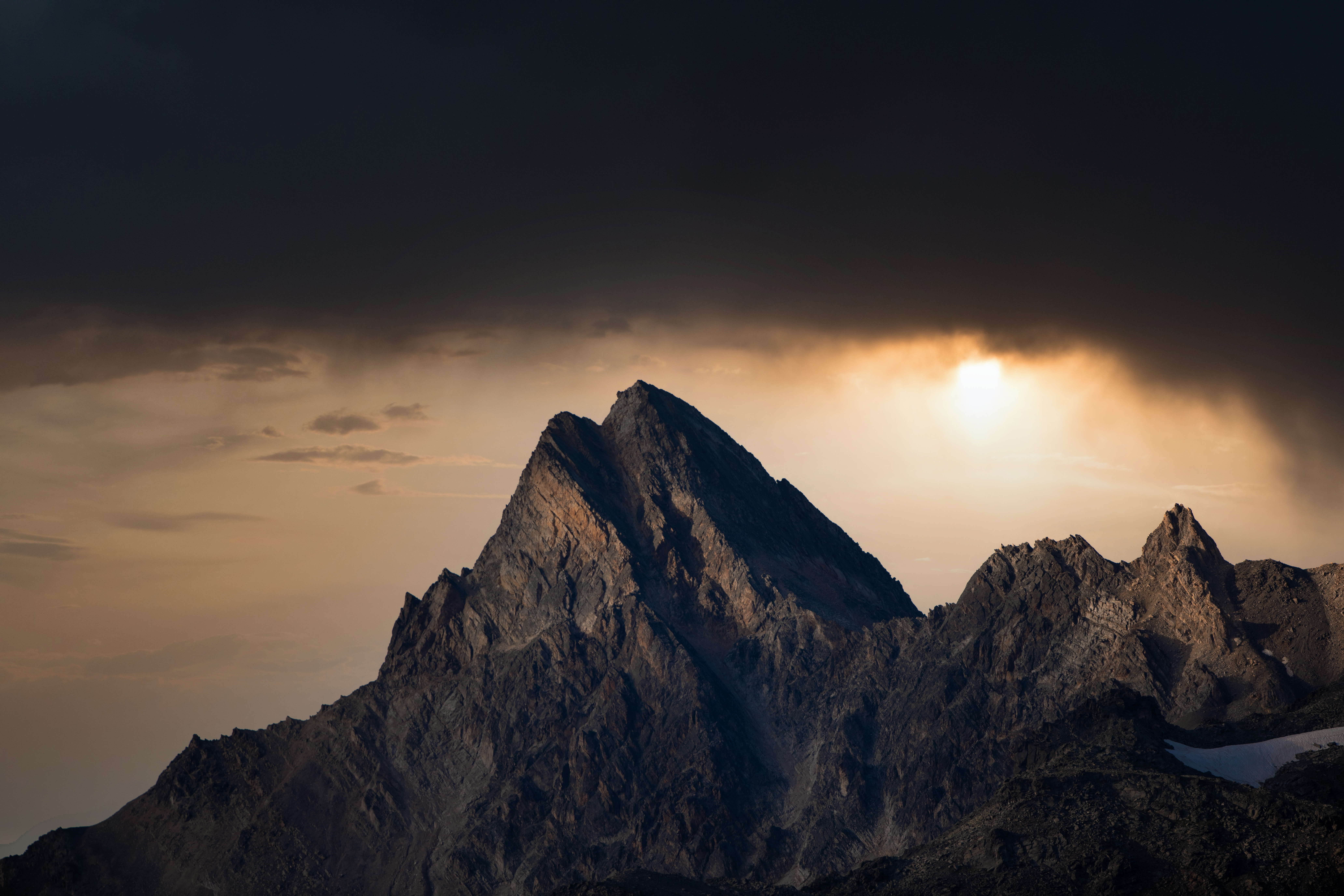 Sommet rocheux éclairé par le soleil sous un ciel sombre