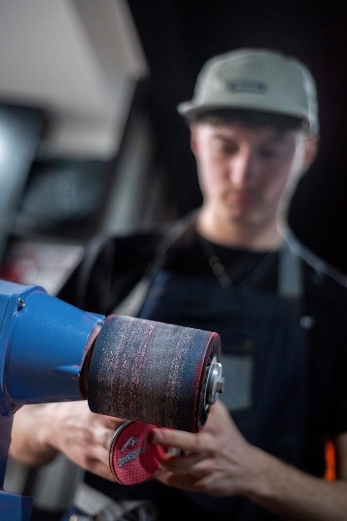 Artisan ponçant une planche en bois dans son atelier
