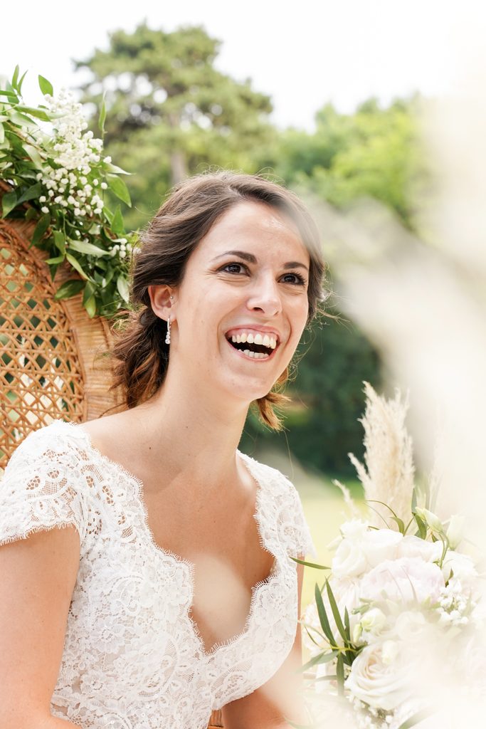 Portrait d’une mariée souriante avec son bouquet