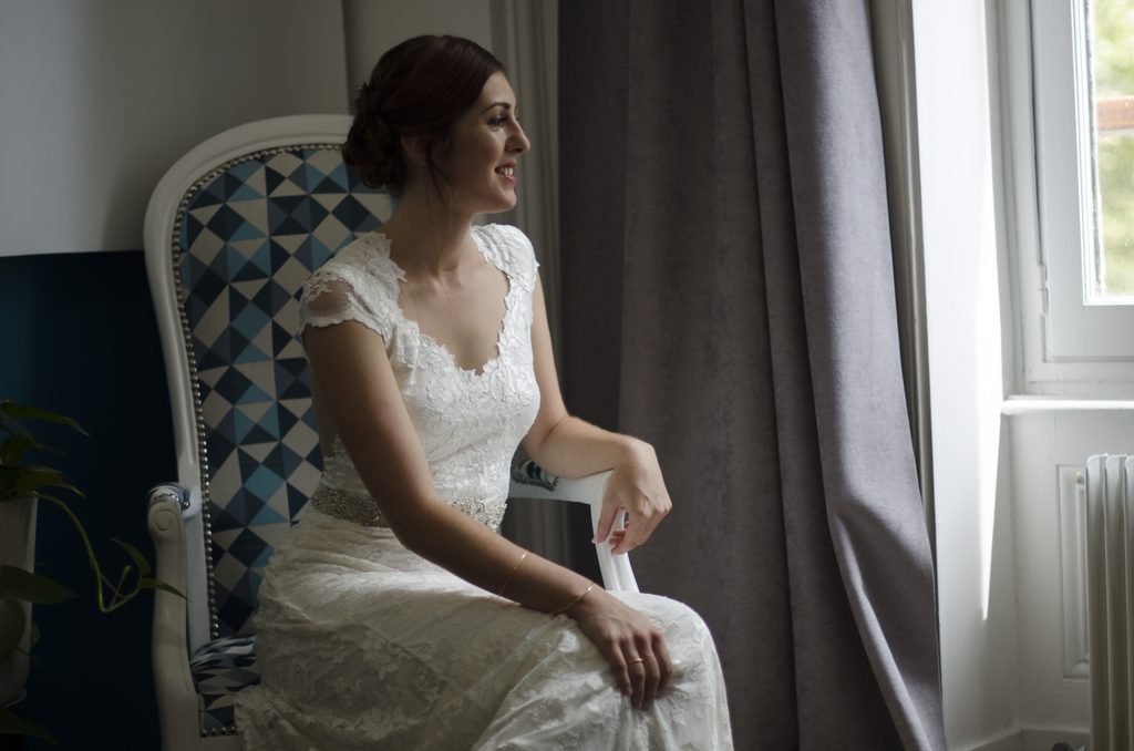 Mariée assise près d’une fenêtre
