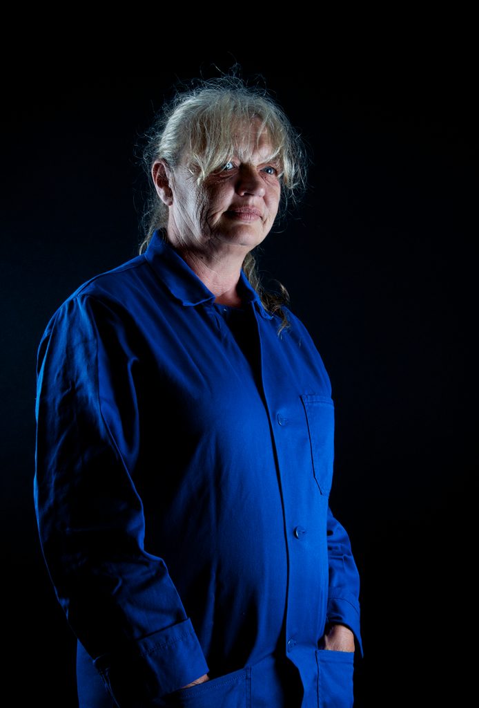 Portrait d’une artisane en blouse bleue sur fond noir