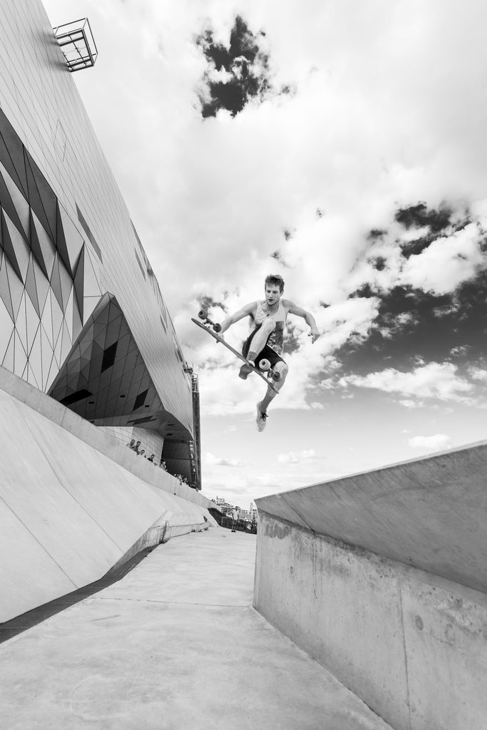 Skateur réalisant un saut devant un bâtiment moderne, en noir et blanc