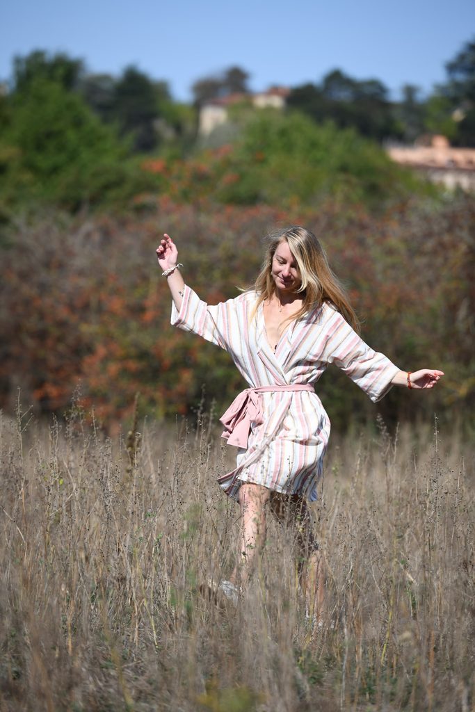 Jeune femme avançant dans une prairie en robe rayée