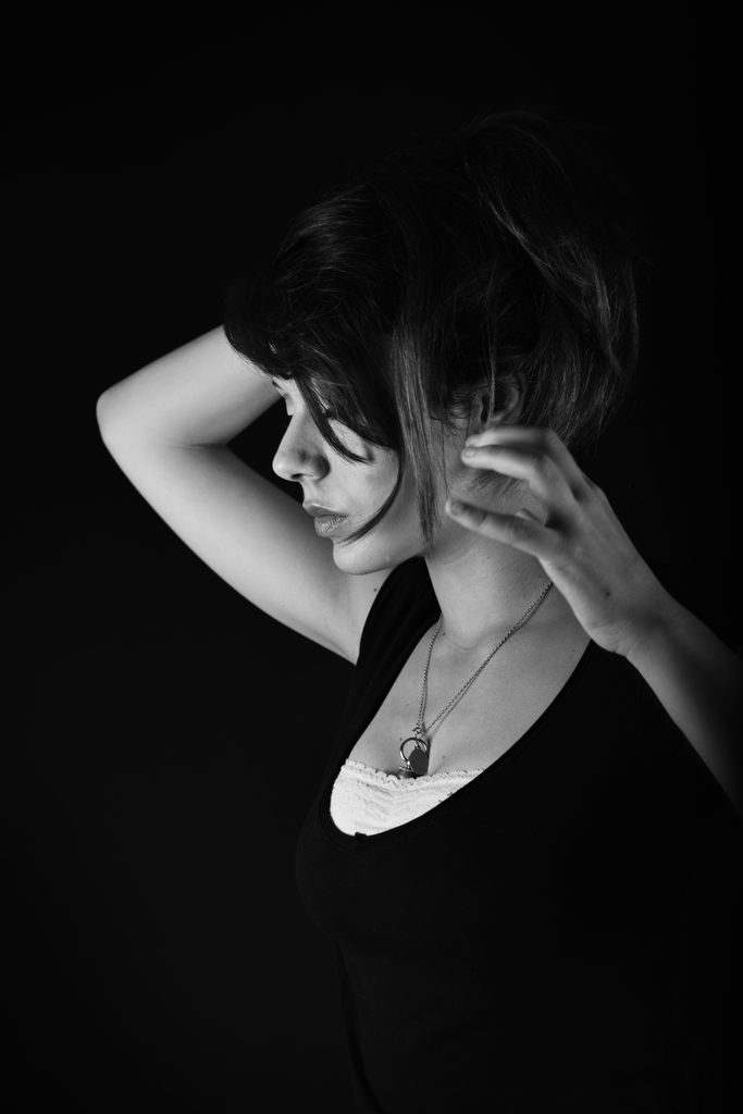 Portrait en noir et blanc d’une jeune femme ajustant ses cheveux